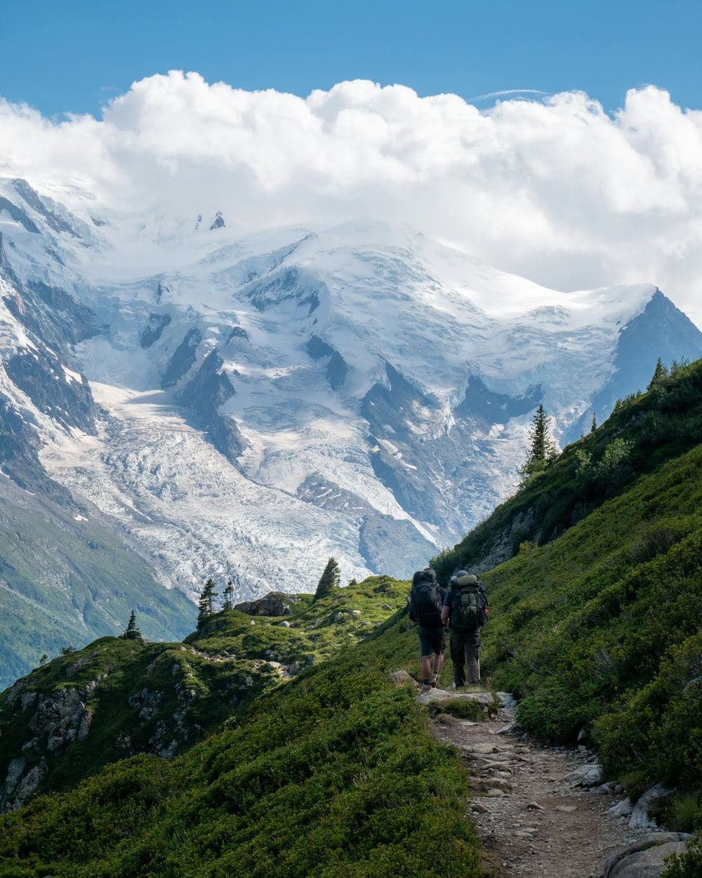 Dos excursionistas con mochila por un sendero de montaña